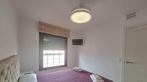 A bedroom with a bed, a window with blinds, a ceiling light, a door, and a small wall-mounted TV. - AL 230 - Apartment near the beach (Vera playa)