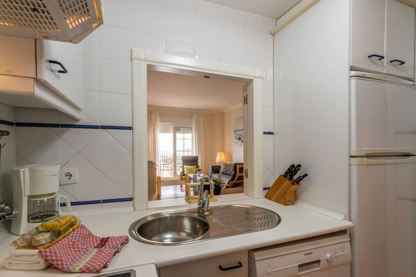 Una cocina con un lavamanos de acero inoxidable, una cafetera y un refrigerador.