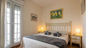 Une chambre à coucher avec un lit, deux tables de chevet avec des lampes, une fenêtre avec des stores et un tableau au mur.