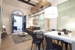 A modern living room with a dining area, featuring a sofa, a coffee table, and a dining table set for four. - Cathedral Apartment - One Bedroom Apartment, Sleeps 2 (Barcelona)