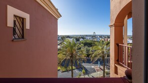 Uma varanda com vista para uma área residencial, palmeiras e céu claro.