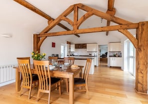 Enjoy meals in this dining area with a wooden table and chairs, surrounded by a high ceiling and open kitchen.