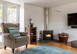 Cozy living room with a fireplace, comfortable armchair, and mounted television.