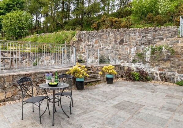 Relax on the patio surrounded by lush greenery and enjoy a meal at the round table.
