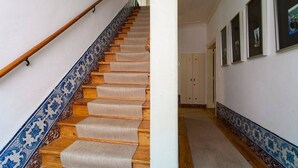 Una scala con un bordo blu e bianco decorativo, gradini in legno e tappeti corridio beige.