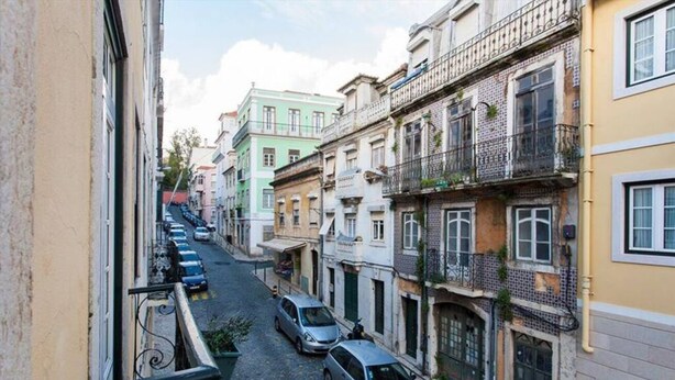 Una stretta via fiancheggiata da edifici a più piani, alcuni con balconi e finestre che si affacciano sulla strada.