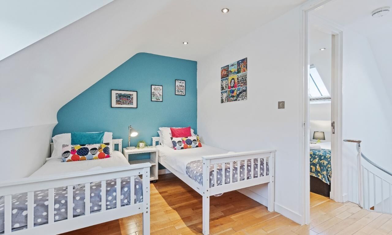 A bedroom with two single beds, a skylight, and a view of another room.