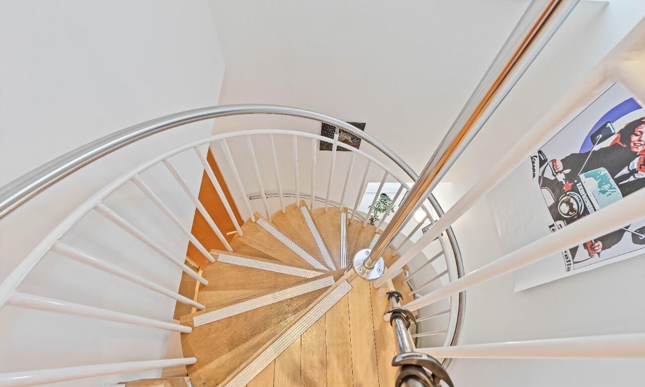 A spiral staircase with wooden steps and white railings.