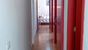 Un couloir aux portes rouges, aux murs blancs et au sol carrelé.