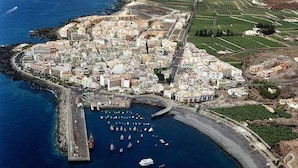 Vue aérienne d’une ville côtière avec un port de plaisance, des bâtiments et une route sinueuse.