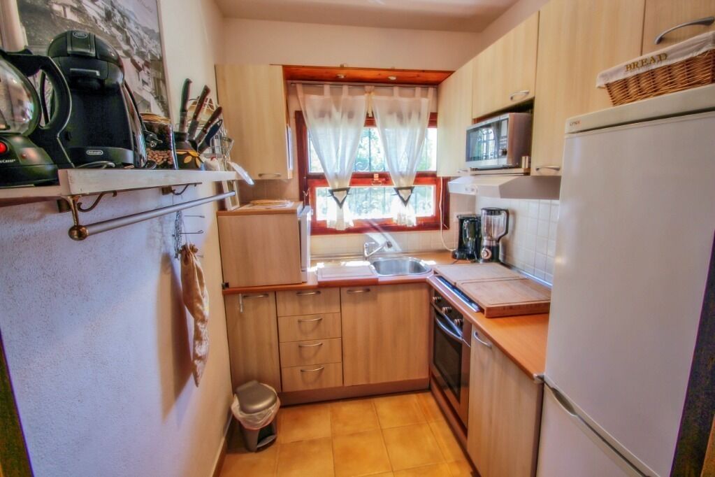 Une cuisine compacte avec des meubles en bois, un four à micro-ondes, un évier et une petite poubelle.