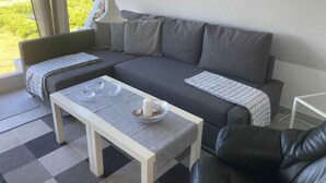 Ein modernes Wohnzimmer mit einem grauen Sofa, einem weißen Couchtisch und einem schwarzen Ledersessel.