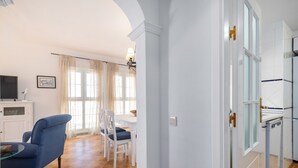 Une pièce comprenant un coin repas, un téléviseur et un meuble blanc.