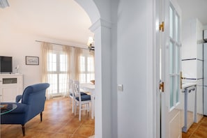 Una habitación con zona de comedor, televisor y un armario blanco.