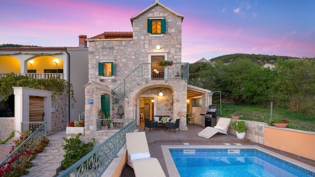 A stone building with a pool, outdoor seating, and a staircase leading to a balcony. - Villa Brač Stone with Swimming Pool (Bol)