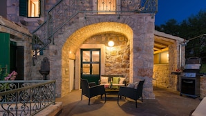 A stone building with a covered patio, outdoor seating, and a grill area. - Villa Brač Stone with Swimming Pool (Bol)