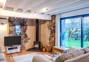 Relax in this inviting living room with a wood-burning stove, flat-screen TV, and comfortable sofa.