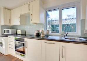 Efficient kitchen with white cabinetry, stainless steel sink, and a window.