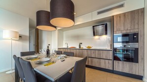 A modern kitchen with a built-in Bosch oven, a dining area with a table set for four, and pendant lighting. - Luxury Apartment the Ocean Dream VII (Primošten)