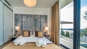 A hotel room with a large bed, two bedside tables with lamps, a view of a body of water through a balcony. - Luxury Apartment the Ocean Dream VII (Primošten)