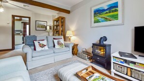 A cozy living room with a sofa, a fireplace, a bookshelf, and a painting on the wall. - Stepping Stones Cottage - sleeps 4 guests  in 2 bedrooms (Blockley)
