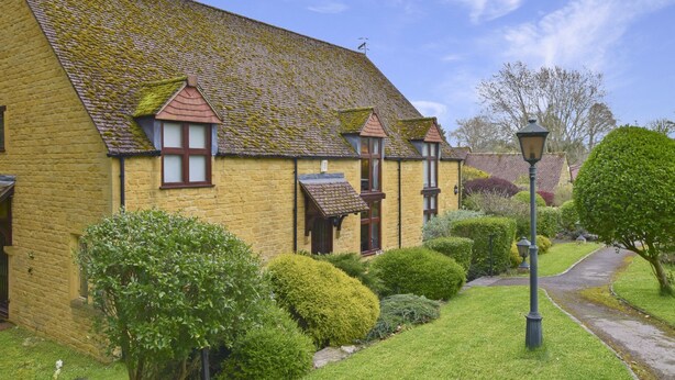 A traditional yellow brick house with a steeply pitched roof, dormer windows, and a well-maintained garden with hedges and a pathway. - Stepping Stones Cottage - sleeps 4 guests  in 2 bedrooms (Blockley)