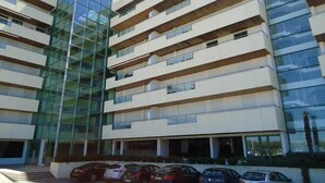 A multi-story building with a glass facade and several balconies. - Luxury apartment in private condominium, with pool (Quarteira)