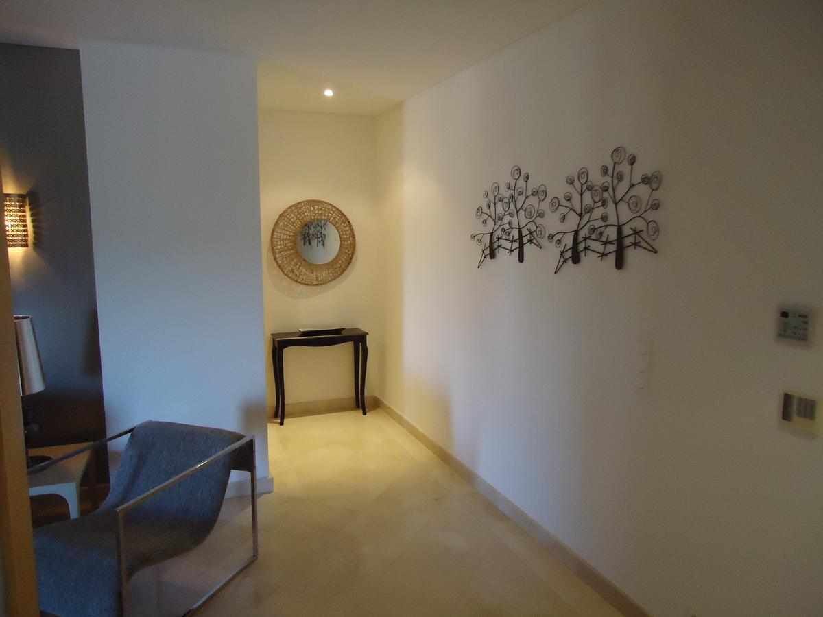 A hallway with a chair, a small table, and wall art.