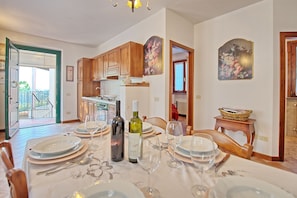 A dining area with a table set for six, a kitchen in the background, and a balcony door. - Casa Vasco - Villa with private pool (Sciano)