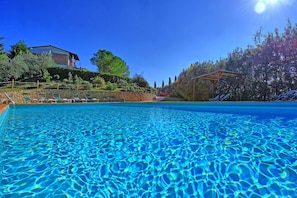 A clear blue swimming pool with lounge chairs and a stone wall in the background. - Casa Vasco - Villa with private pool (Sciano)