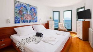 A bedroom with a bed, a dresser, a chair, a TV, and a painting. - Beachfront Villa Shades of Summer (Podaca)