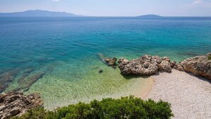 A coastal landscape with clear turquoise waters, rocky formations, and a pebbly beach. - Beachfront Villa Shades of Summer (Podaca)