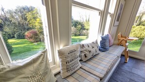 A cozy seating area with a bench, pillows, and a small table. - Downedge -  a house that sleeps 13 guests  in 6 bedrooms (Sandown)