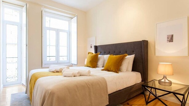 Een slaapkamer met een bed, nachtkastje en raam.