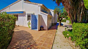A white building with a blue-tiled entrance, surrounded by greenery and a tiled patio. - Kathrin - beautiful little house in pretty grounds with lovely views in Benissa (Benissa)