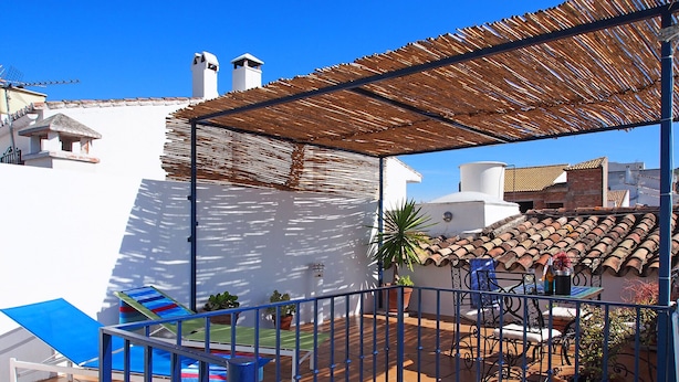 A rooftop terrace with a blue chair, a small play area, and potted plants.