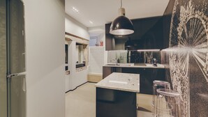 A modern kitchen with a central island, bar stools, and a large pendant light. - Master Deco Gem in Bica (Lisboa)