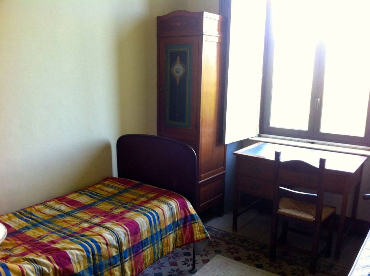 A room with a bed, a desk, and a wardrobe.