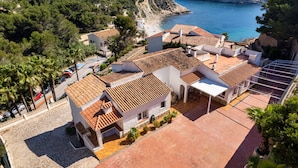 A coastal building with terracotta roofs, a paved courtyard, and a view of the sea. - Casa Luna - Javea, Costa Blanca (Javea)