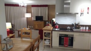 A compact living space with a dining area, kitchen, and a television.