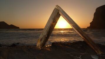 A wooden structure on a beach at sunset with the sun behind it.