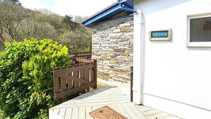 Eine Steinmauer mit einem Holztor, ein weißes Gebäude mit blauem Dach und ein Schild mit der Aufschrift "Garyvoe".