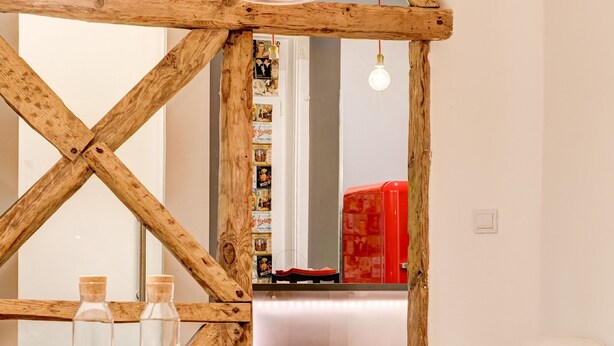 Un área de comedor con estructura de techo de madera, mesa y sillas blancas.