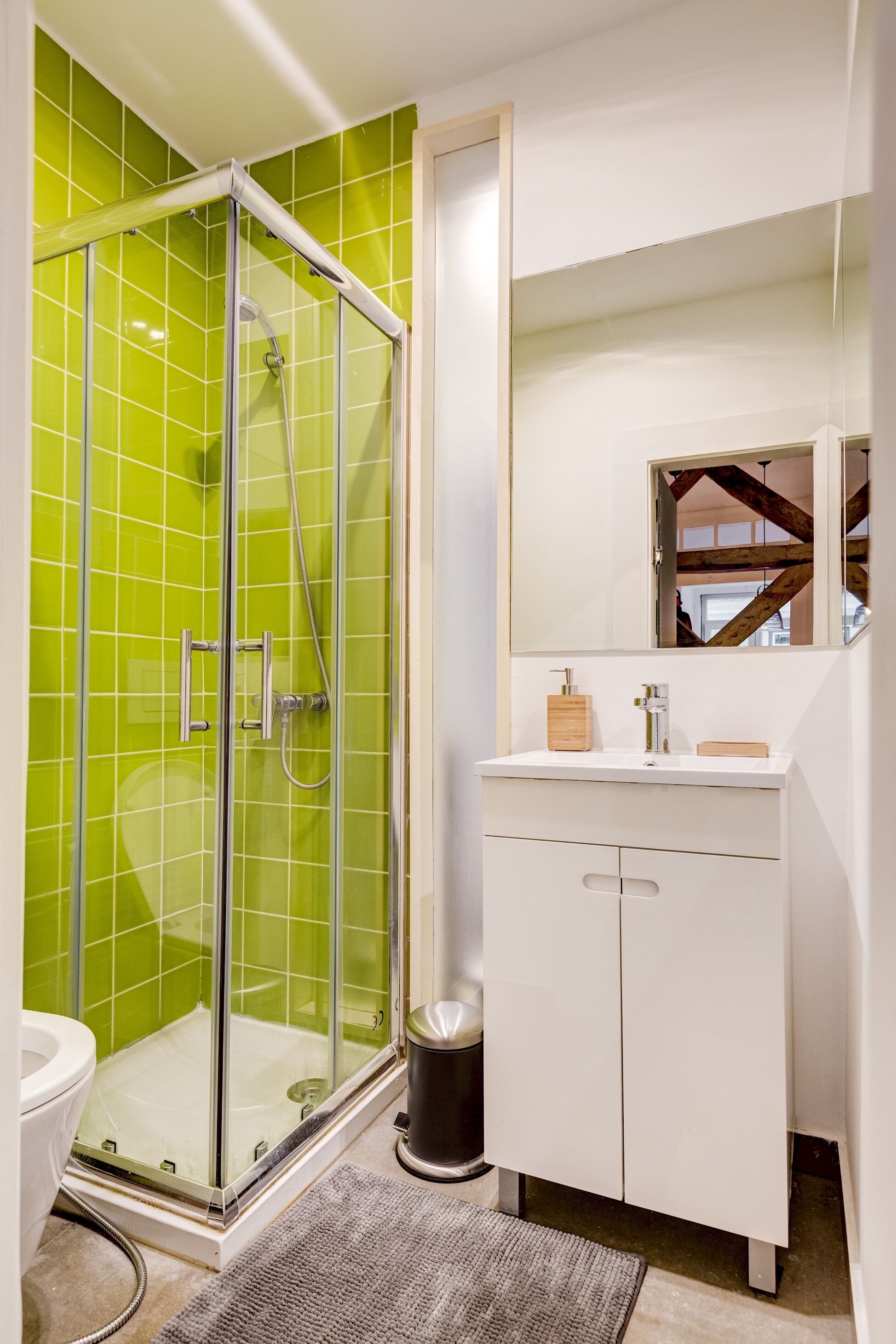 A bathroom with a glass-enclosed shower, a white sink, and a mirror above it.
