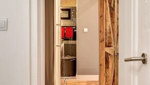 Un pasillo estrecho que conduce a una cocina con electrodomésticos modernos y suelo de madera.