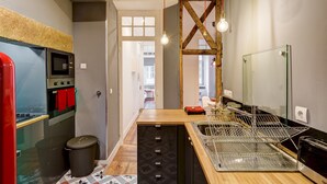 Cocina moderna con microondas, horno y fregadero integrados. Cuenta con una encimera de madera y un cubo de basura.