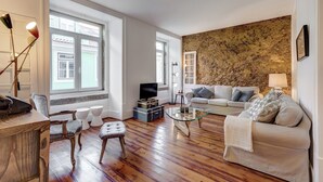Amplia sala de estar con un ventanal, una pared de acento de piedra, un sofá, una mesa de centro y un televisor.
