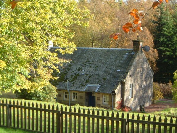 A stone building with a sloped roof, a small window, and a chimney.
