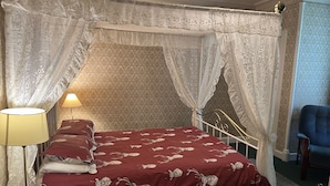 Une chambre à coucher avec un lit à baldaquin, une lampe de chevet et un fauteuil.