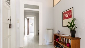 A hallway with a wooden bookshelf, a radiator, and a framed picture on the wall.